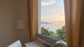 Ein Zimmer mit einem weißen Schreibtisch, einem gestreiften Stuhl, einem Globus und Blick auf ein Gewässer und viel Grün.