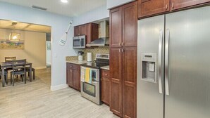 Una cucina moderna con mobili in legno, elettrodomestici in acciaio inossidabile e un'area pranzo con tavolo e sedie.