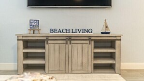 Un tavolo consolle in legno con un cartello che riporta la scritta 'BEACH LIVING' e un piccolo modellino di barca a vela.