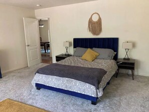 A bedroom with a bed, two bedside tables, a wall-mounted lamp, and a door leading to another room. - The Creek House in the heart of gold country (Challenge-Brownsville)