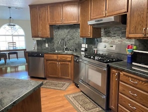 A kitchen with wooden cabinets, a stainless steel stove, and a dishwasher. - The Creek House in the heart of gold country (Challenge-Brownsville)