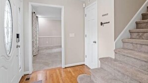 A hallway with a carpeted staircase, a door with a keyhole, and a door with a handle. - Beautiful Home Walking Distance to Elon University (Elon)