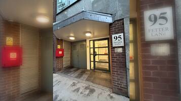 A property entrance with a number sign, a fire alarm box, and a gated door.