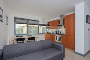 A modern kitchen with wooden cabinets, a built-in oven, and a window overlooking the city.