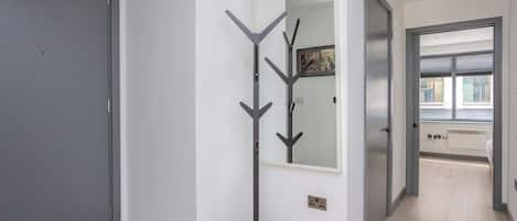 A hallway with a coat rack, a door, and a window.