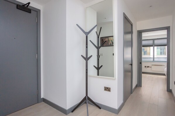 A hallway with a coat rack, a door, and a window.