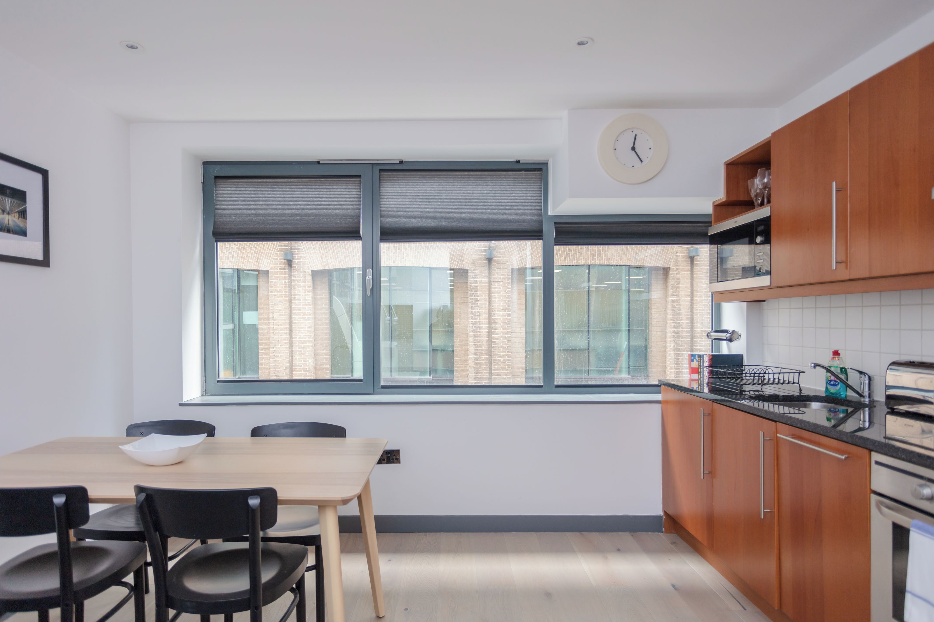Una cocina moderna con armarios de madera, horno empotrado y ventana con persianas.