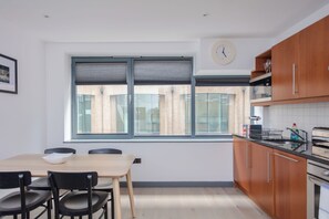 A modern kitchen with wooden cabinets, a built-in oven, and a window with blinds.