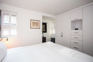 A bedroom with a bed, a wardrobe, a framed map, and a window with blinds.