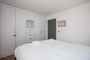 A bedroom with a bed, white wardrobe, and a door.