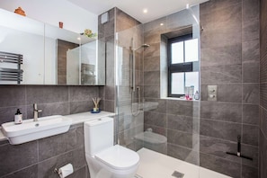 A modern bathroom with a glass-enclosed shower, a white sink, and a toilet.