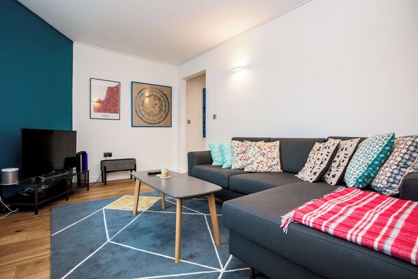 A modern living room with a sofa, a coffee table, a TV, and a map on the wall.