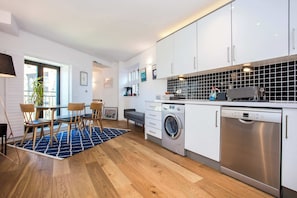 A modern kitchen with white cabinets, a washing machine, and a dishwasher.