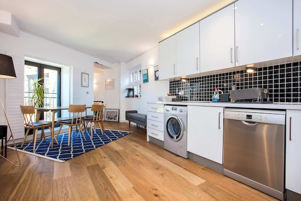 A modern kitchen with white cabinets, a washing machine, and a dishwasher.