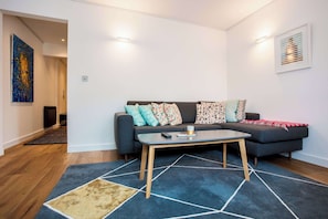 A modern living room with a sofa, coffee table, and a rug.