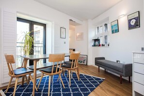 A modern living room with a dining area, a bench, and a white cabinet.