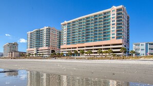 A beachfront hotel with multiple high-rise buildings, a sandy beach, and palm trees. - 2BD Ocean View-Lazy River/Hot Tubs/Indoor Pool (North Myrtle Beach)