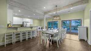 Una cocina amplia con armarios blancos, un comedor con mesa y sillas de madera, y un ventanal con vistas al exterior.