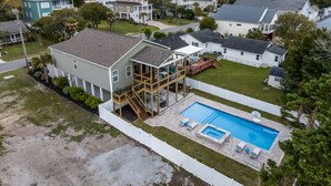 Una propiedad residencial con una casa de dos pisos, una terraza, una piscina y un patio cercado.