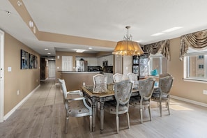 A spacious kitchen with modern appliances, a dining area with a large table and chairs, and a chandelier.