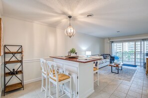 A spacious living area with a kitchen island, white furniture, and a balcony with a view. - Windy Hill-2BD Ocean View Condo - Snowbird Special (North Myrtle Beach)