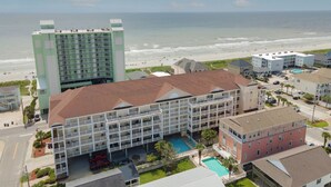 Un hôtel à plusieurs étages, doté d’une piscine et offrant une vue sur la plage et l’océan.