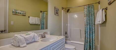 A bathroom with a double sink vanity, a toilet, and a shower with a curtain.