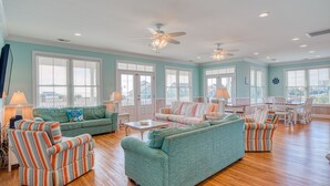 Een ruime woonkamer met turquoise wanden, houten vloeren en een combinatie van gestreept en effen meubilair.