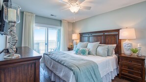 A bedroom with a bed, nightstands, a ceiling fan, and a window with curtains. - Sea Oats D-3, 3BD 2BA Oceanfront Paradise (North Myrtle Beach)