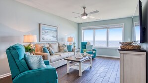 A living room with teal armchairs, a beige sofa, a wooden coffee table, and a ceiling fan. - Sea Oats D-3, 3BD 2BA Oceanfront Paradise (North Myrtle Beach)