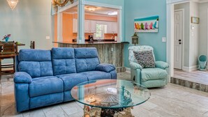 A spacious living room with a blue sofa, a glass coffee table, and a ceiling fan. - 4BD Beach House-Private Pool-3 Min Walk 2Beach (North Myrtle Beach)