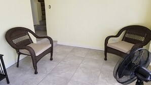 Two wicker chairs with beige cushions in a room with tiled flooring and a standing fan. - Apartment with bath, tv, ac and a view to die for (Estate Bovoni)