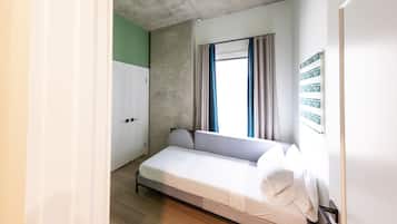 A small, single-bed room with a window, a wardrobe, and a wall with 'HELLO' signs.