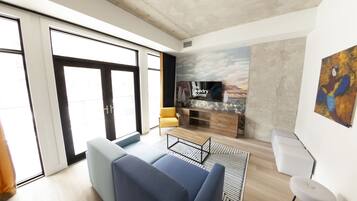 A modern living room with a sofa, a coffee table, a TV, and a fireplace.