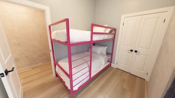 A bunk bed in a room with wooden flooring and a white door.