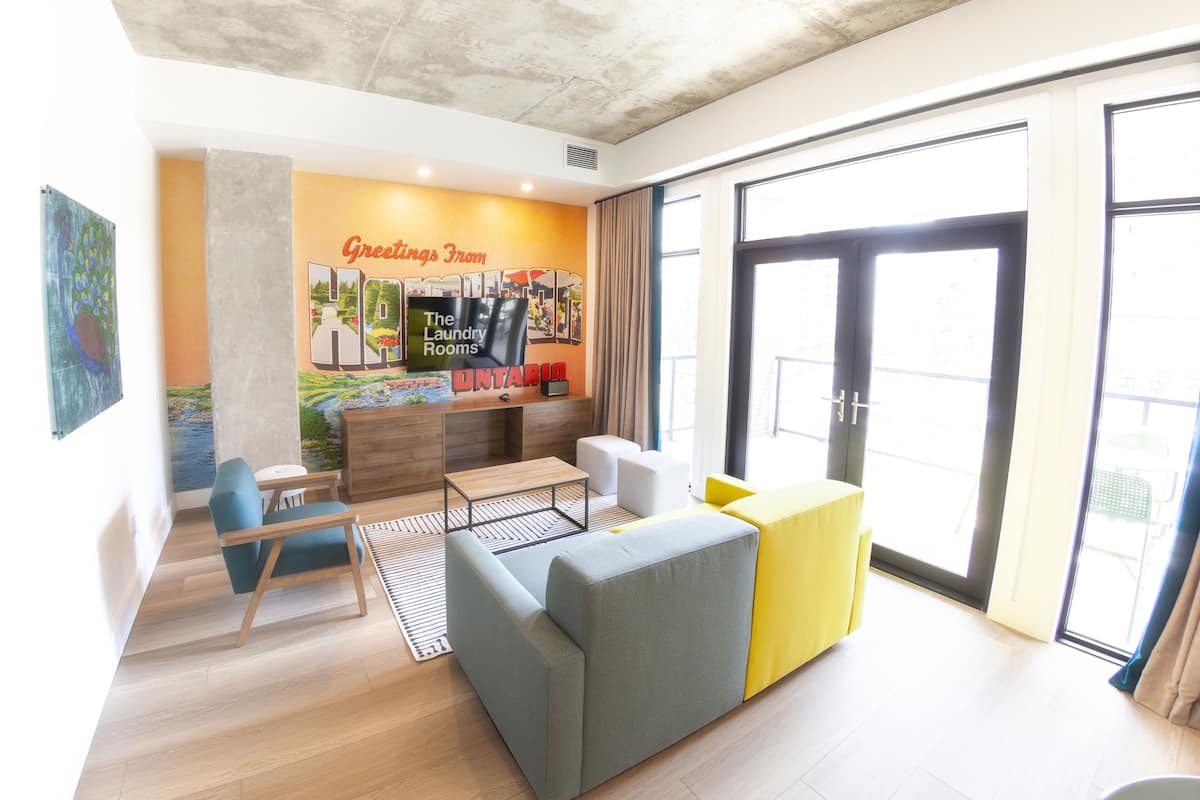 Un moderno vestíbulo de hotel con un amplio ventanal, una recepción y un mural colorido.