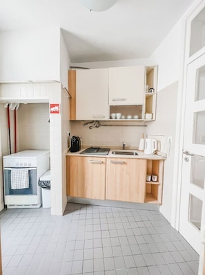 A compact kitchen with a sink, cabinets, and a coffee machine.
