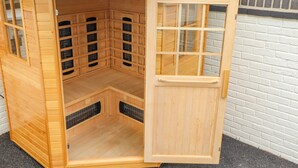 Een houten sauna met een schuifdeur, meerdere banken en een schuin dak.