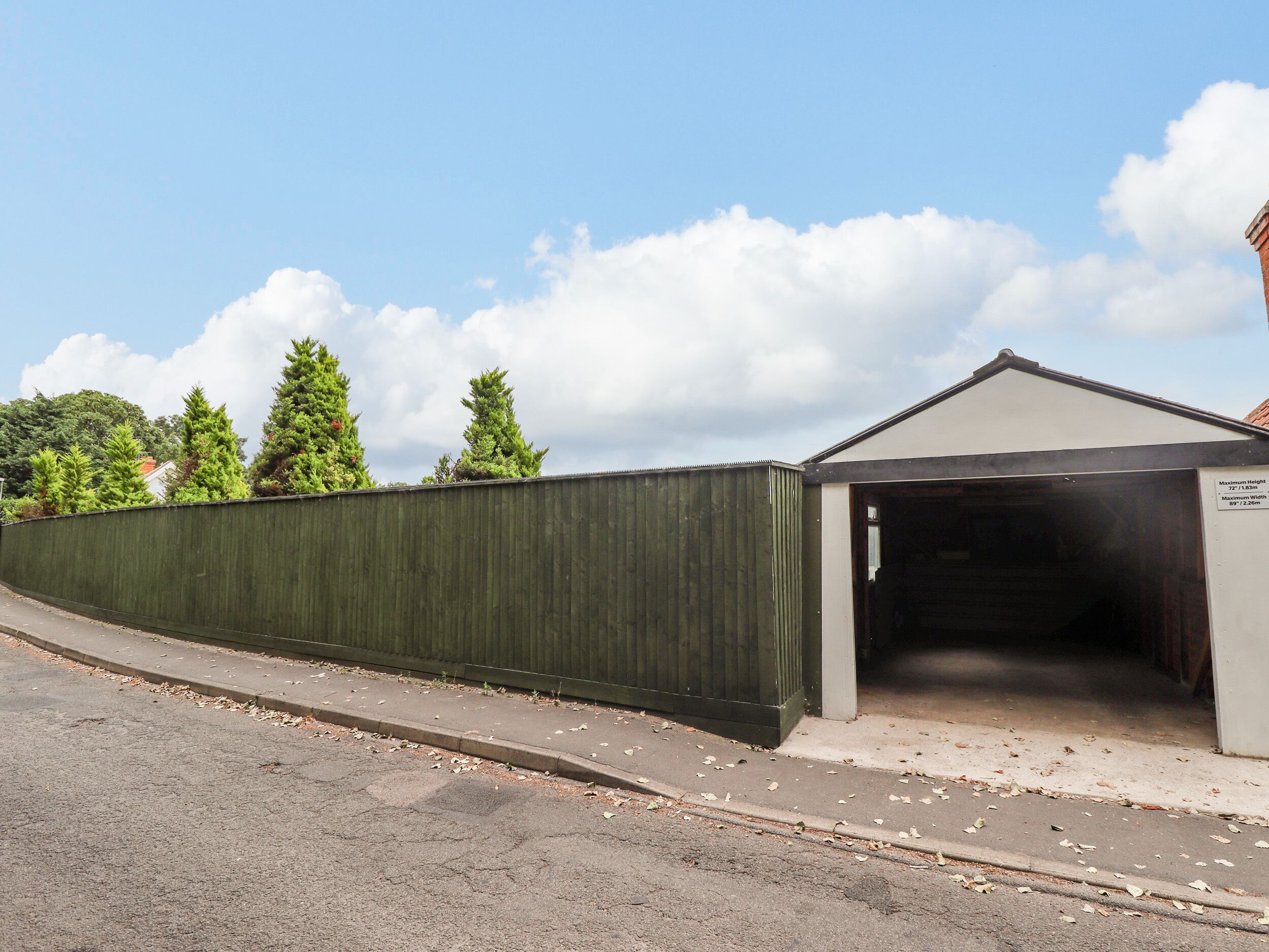 A building with a covered entrance and a green fence.