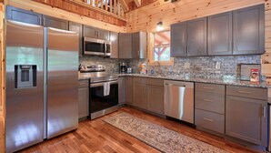 Une cuisine moderne dotée d’appareils électroménagers en acier inoxydable, de plans de travail en granit et de meubles en bois.