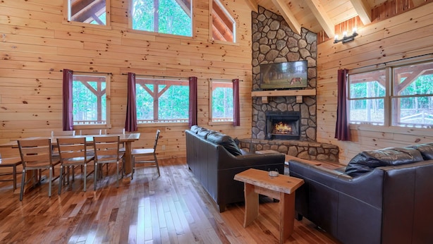 L’intérieur d’un chalet en bois, avec une cheminée en pierre, des meubles en bois et de grandes fenêtres.