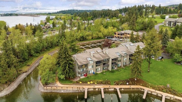 A lakeside hotel with multiple buildings, a dock, and surrounding greenery. - Waterfront Condo, Flathead Lake and Mountain Views! (Bigfork)