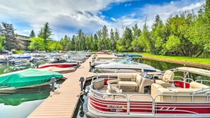 A marina with several boats docked, a wooden pier, and a backdrop of trees and a partly cloudy sky. - Waterfront Condo, Flathead Lake and Mountain Views! (Bigfork)