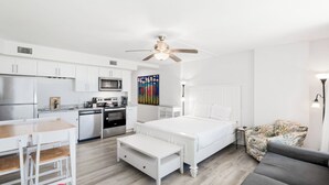 Um espaço de estar moderno e compacto, com cozinha compacta, cama, área de refeições e espaço para sentar.
