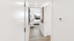 Um corredor com uma cama, uma mesa e um quadro na parede.