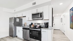 Uma cozinha moderna com armários brancos, eletrodomésticos de aço inoxidável e bancada de granito.