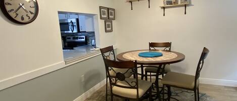 Un coin repas comprenant une table ronde, quatre chaises, une horloge et un ventilateur de plafond.