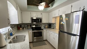A modern kitchen with stainless steel appliances, white cabinets, and a granite countertop. - Your piece of Paradise at Palm Manor Condo (Englewood)