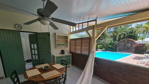 A dining area with a table and chairs, a ceiling fan, a hammock, and a view of a swimming pool. - CHARMING HOUSE WITH POOL 5 MINUTES FROM THE BEACH! (LE GOSIER)