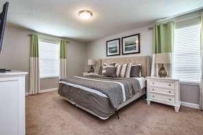A bedroom with a bed, nightstands, a dresser, and two framed pictures on the wall. - 6BR Disney Pool Home | 3 King Bedrooms | Private Pool & Spa | Sleeps 14 (Kissimmee)